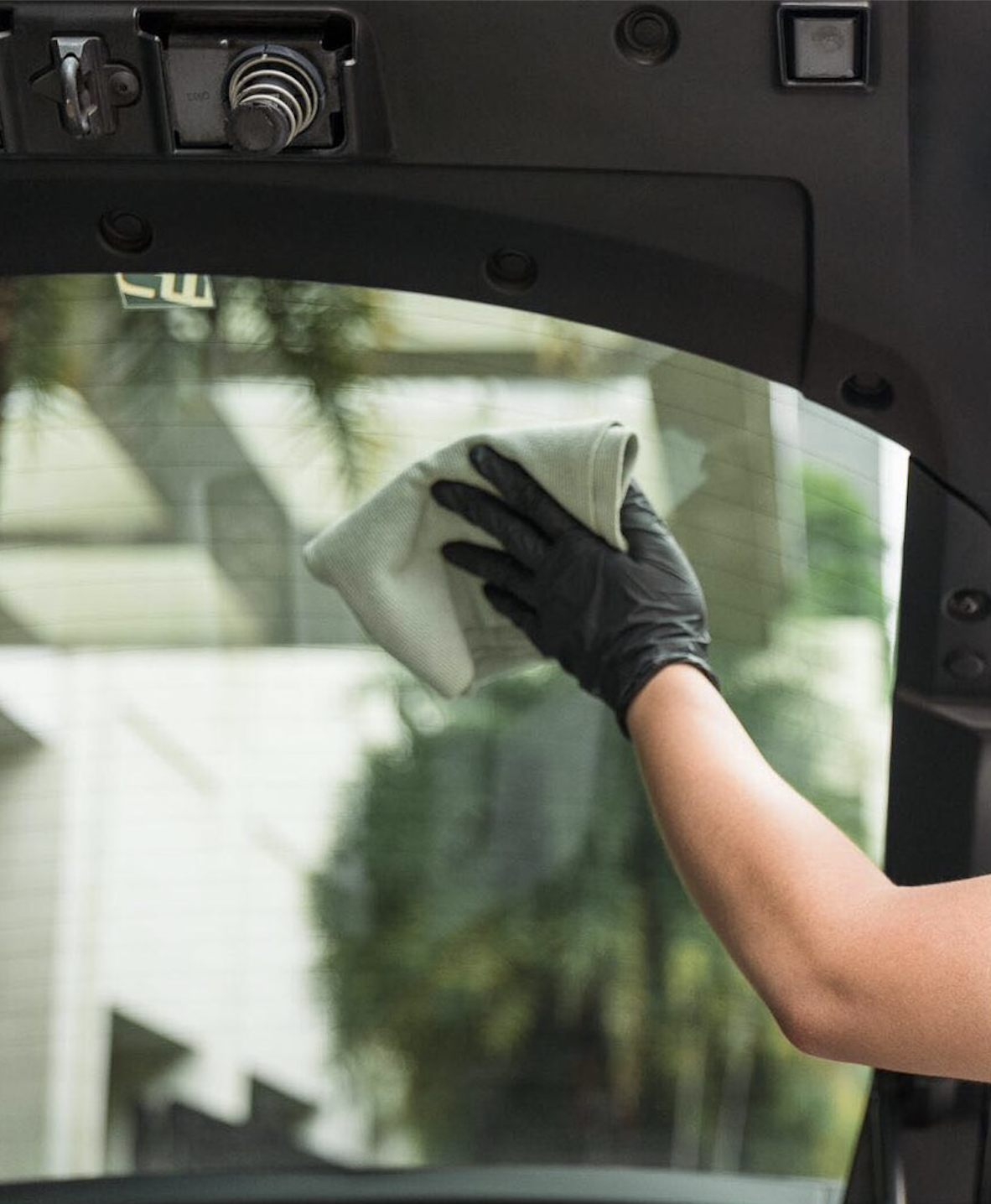 Gloved hand wiping the inside of a rear tailgate window